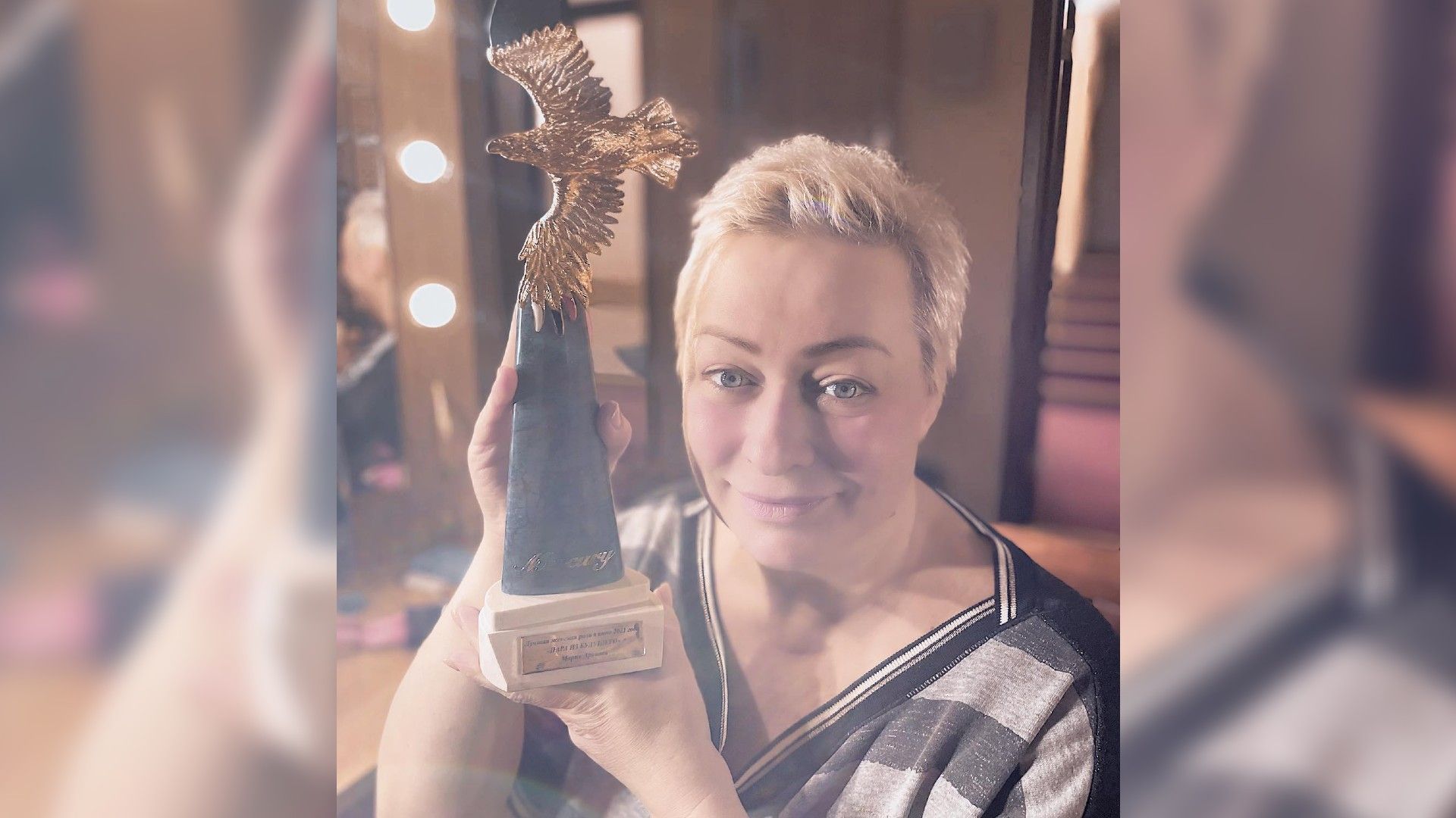 Марина Аронова с короткими светлыми волосами держит в руках кинопремию «Золотой орёл»