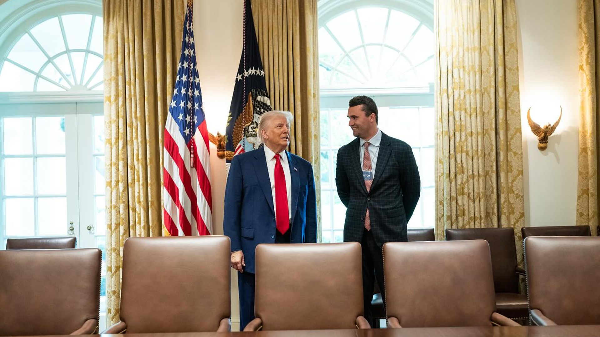 Чарли Кирк и Дональд Трамп стоят друг напротив друга в официальной обстановке
