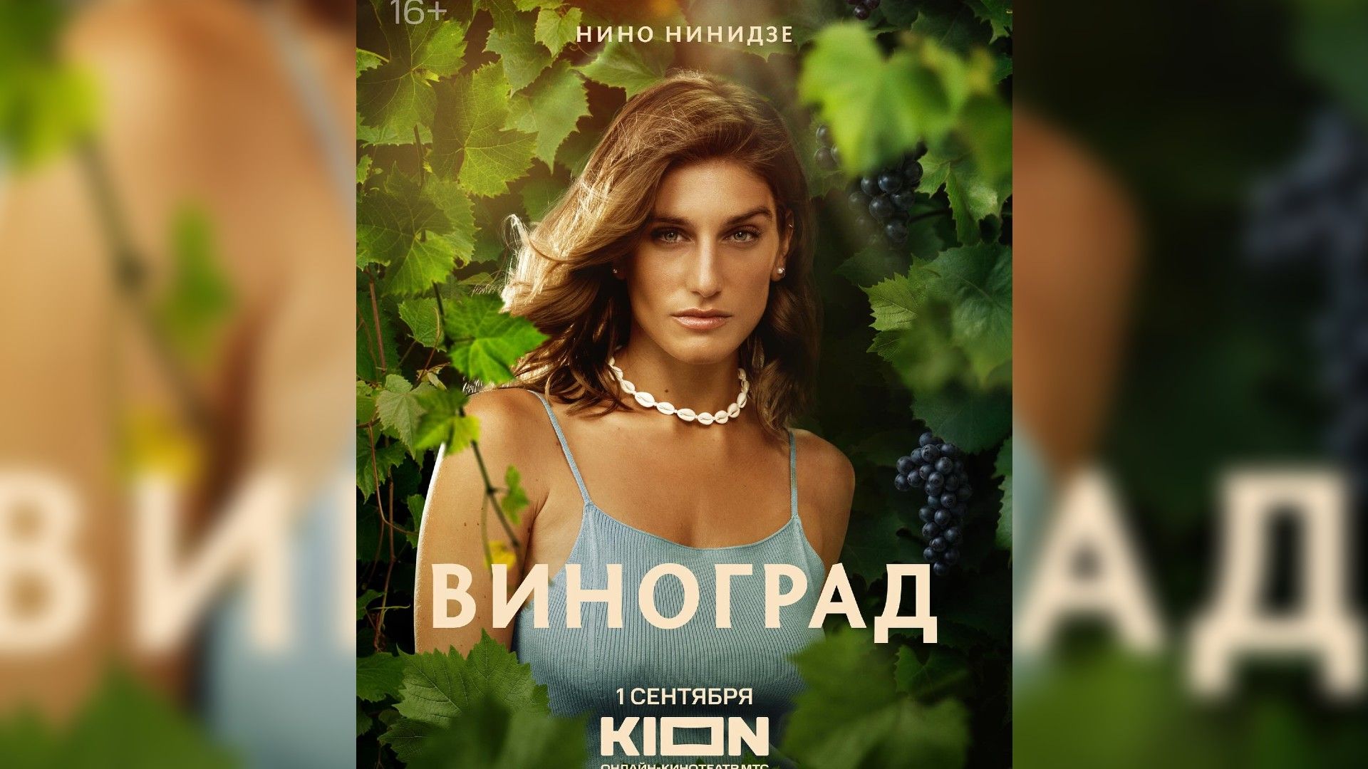 Нино Нинидзе в голубом платье и ожерелье из ракушек стоит среди виноградных листьев на постере сериала Виноград