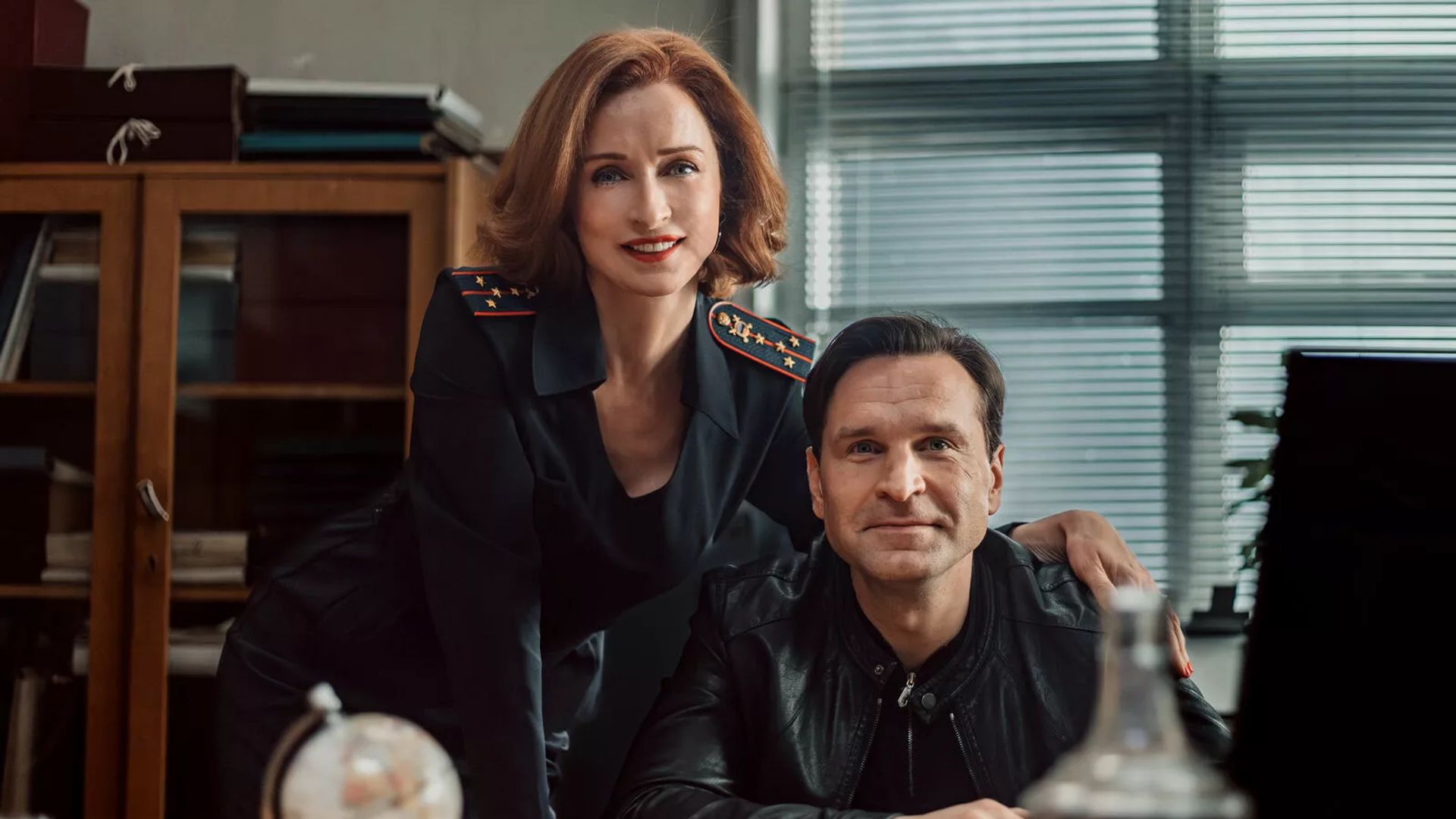 Екатерина Стулова и Виктор Добронравов в полицейской форме улыбаются на камеру в кабинете полиции