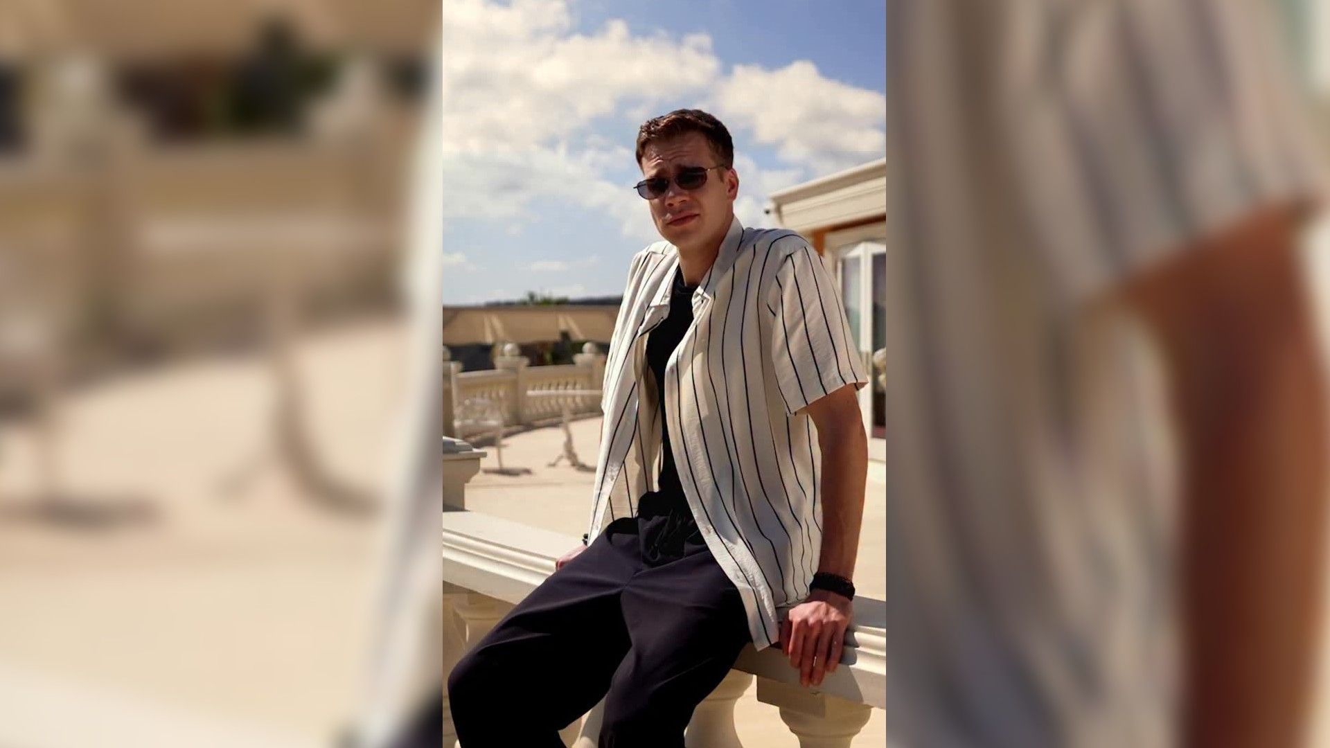 Кузьма Сапрыкин в солнечных очках сидит на поребрике