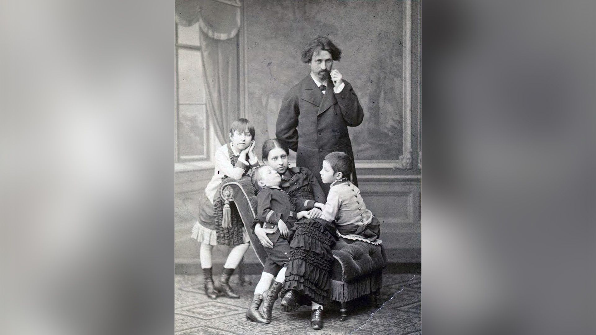 Вера Репина сидит на кресле с двумя детьми, рядом стоит Илья Репин и их старшая дочь