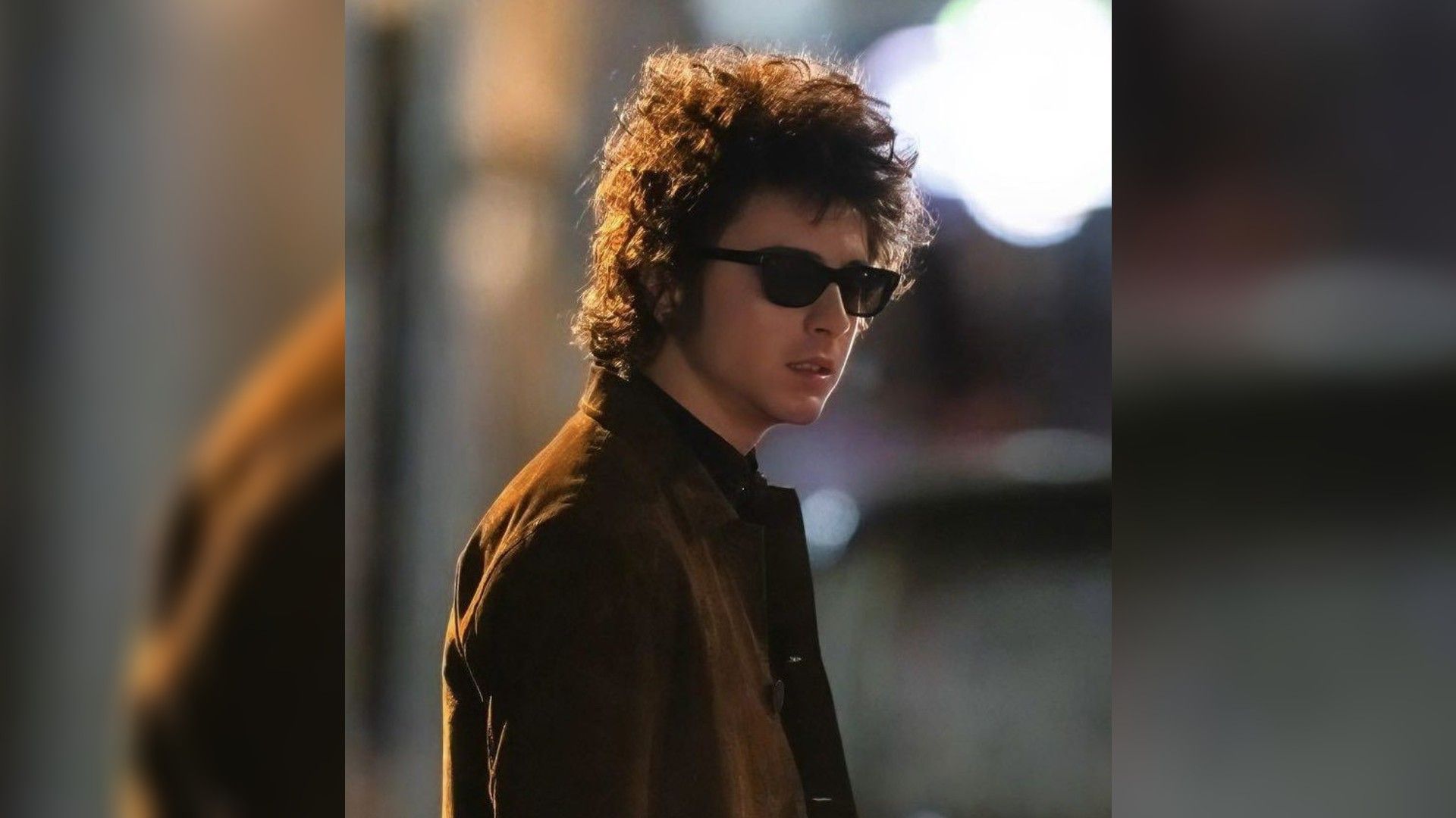 Тимоти Шаламе в солнечных очках и куртке стоит в профиль