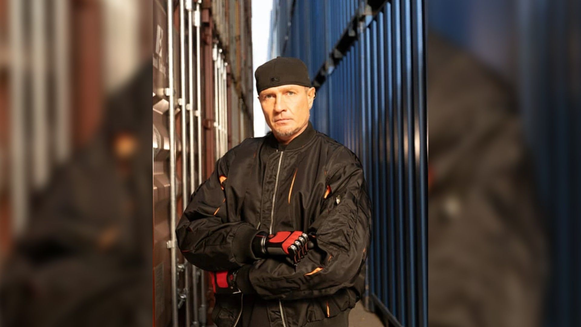 Роман Костомаров с протезами вместо рук стоит на фоне грузовых контейнеров