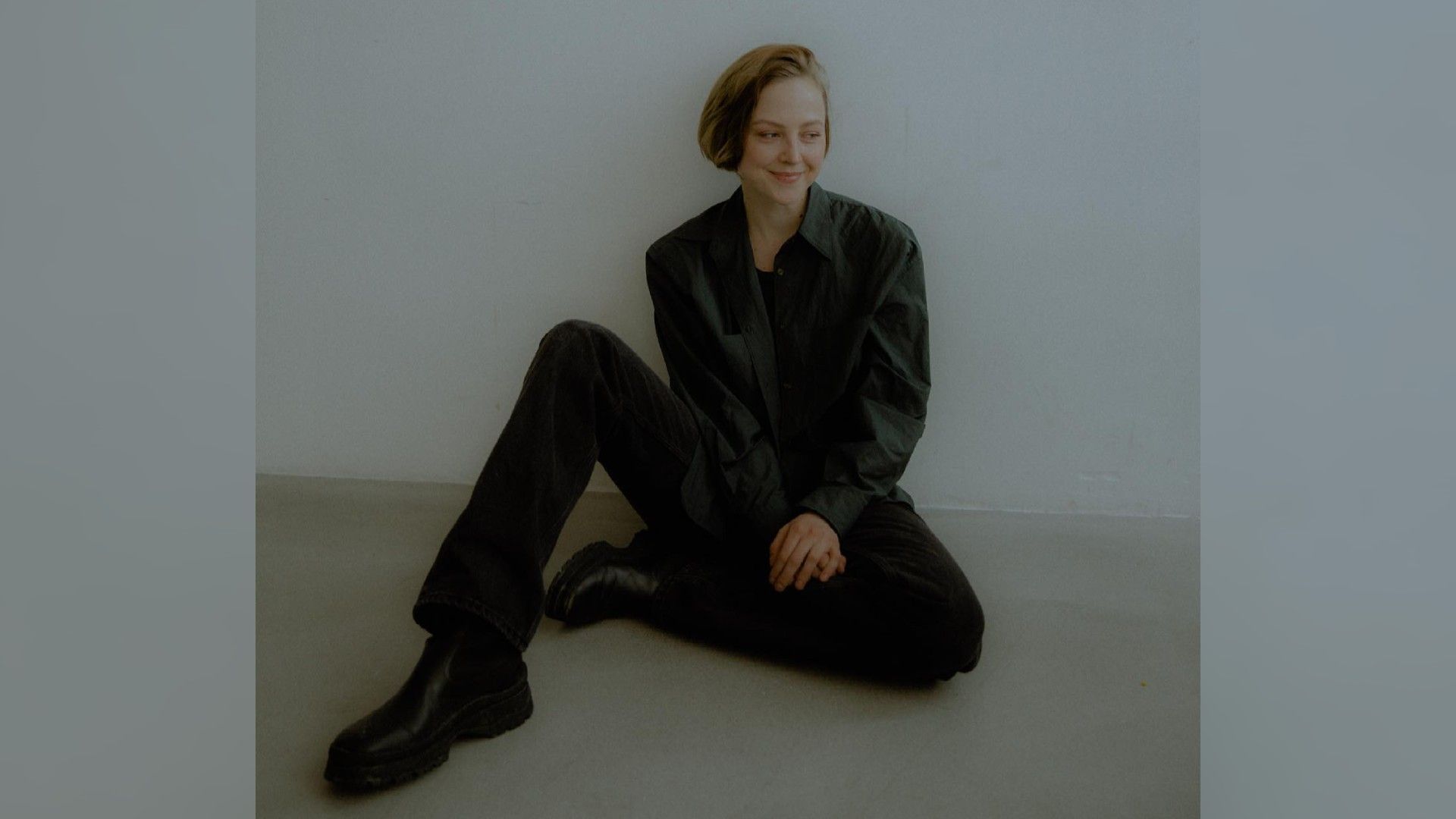 Нина Гусева в чёрном наряде сидит на полу