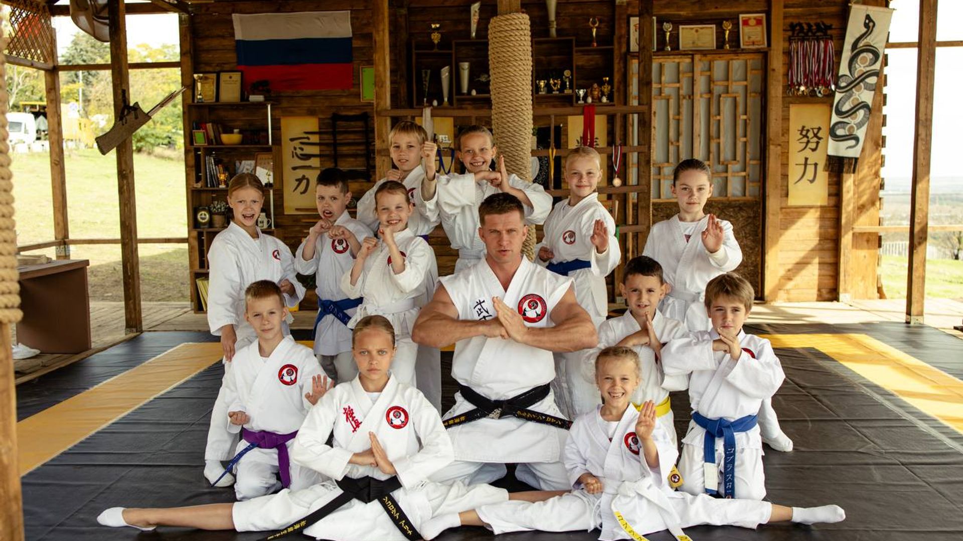 Роман Курцын в спортивной форме в окружении маленьких каратистов