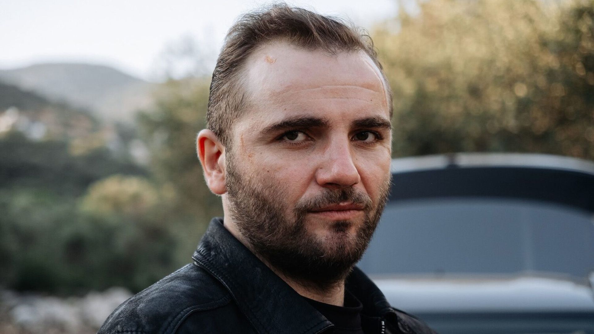 Максим Стоянов в черной кожаной куртке крупным планом