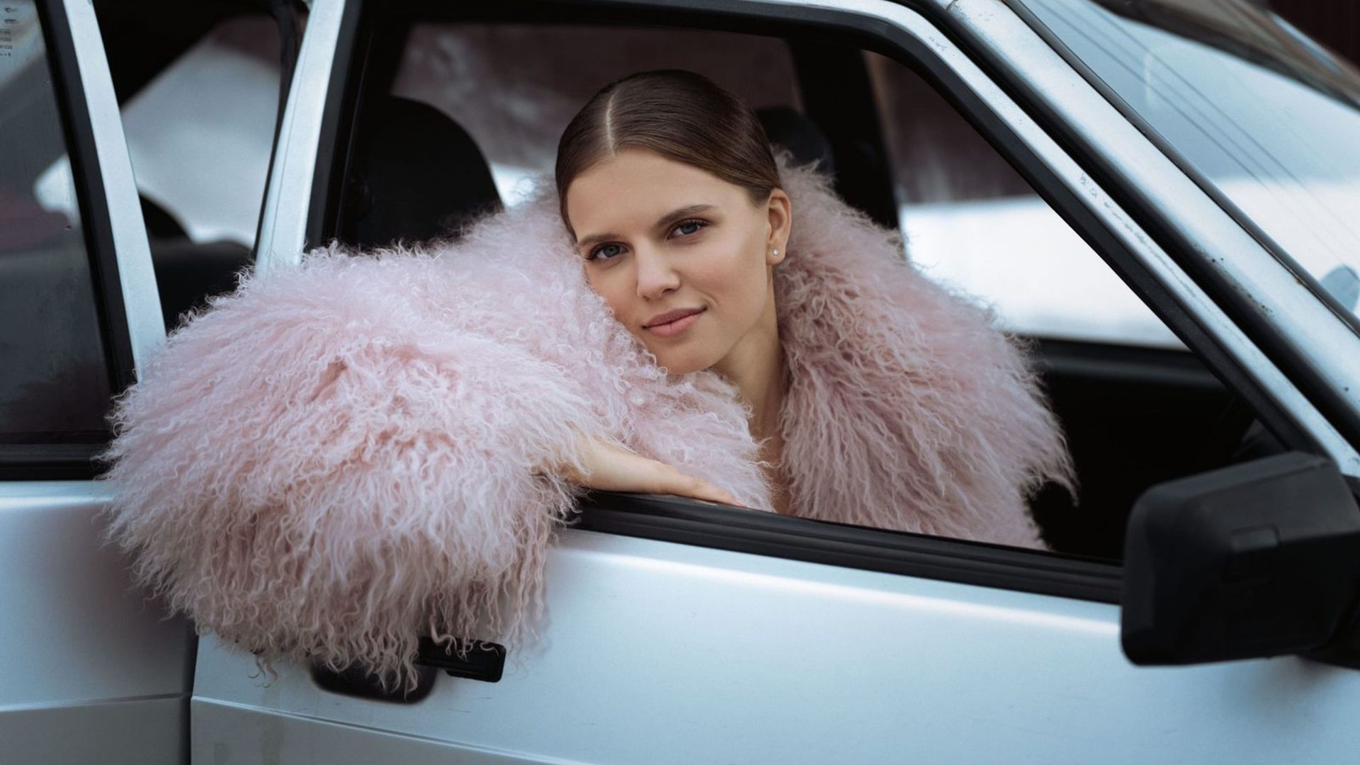 Ника Здорик в розовой шубе выглядывает из окна автомобиля
