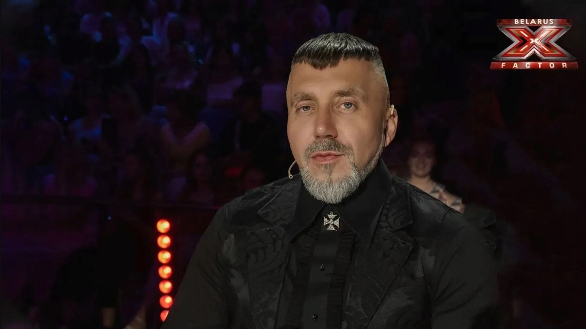 Сергей Пархоменко, одетый в черные пиджак и рубашку, в студии шоу "Фактор.BY"