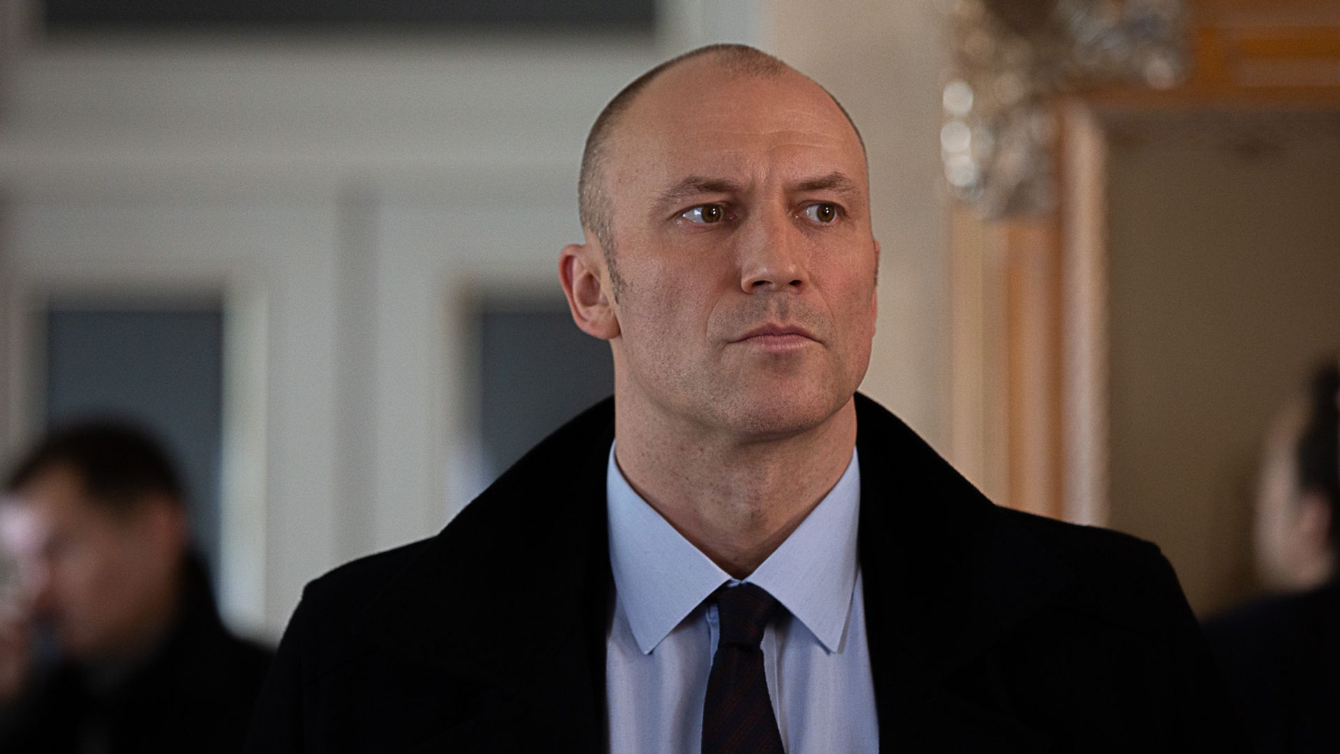 Константин Соловьёв в рубашке и пальто строго смотрит вдаль