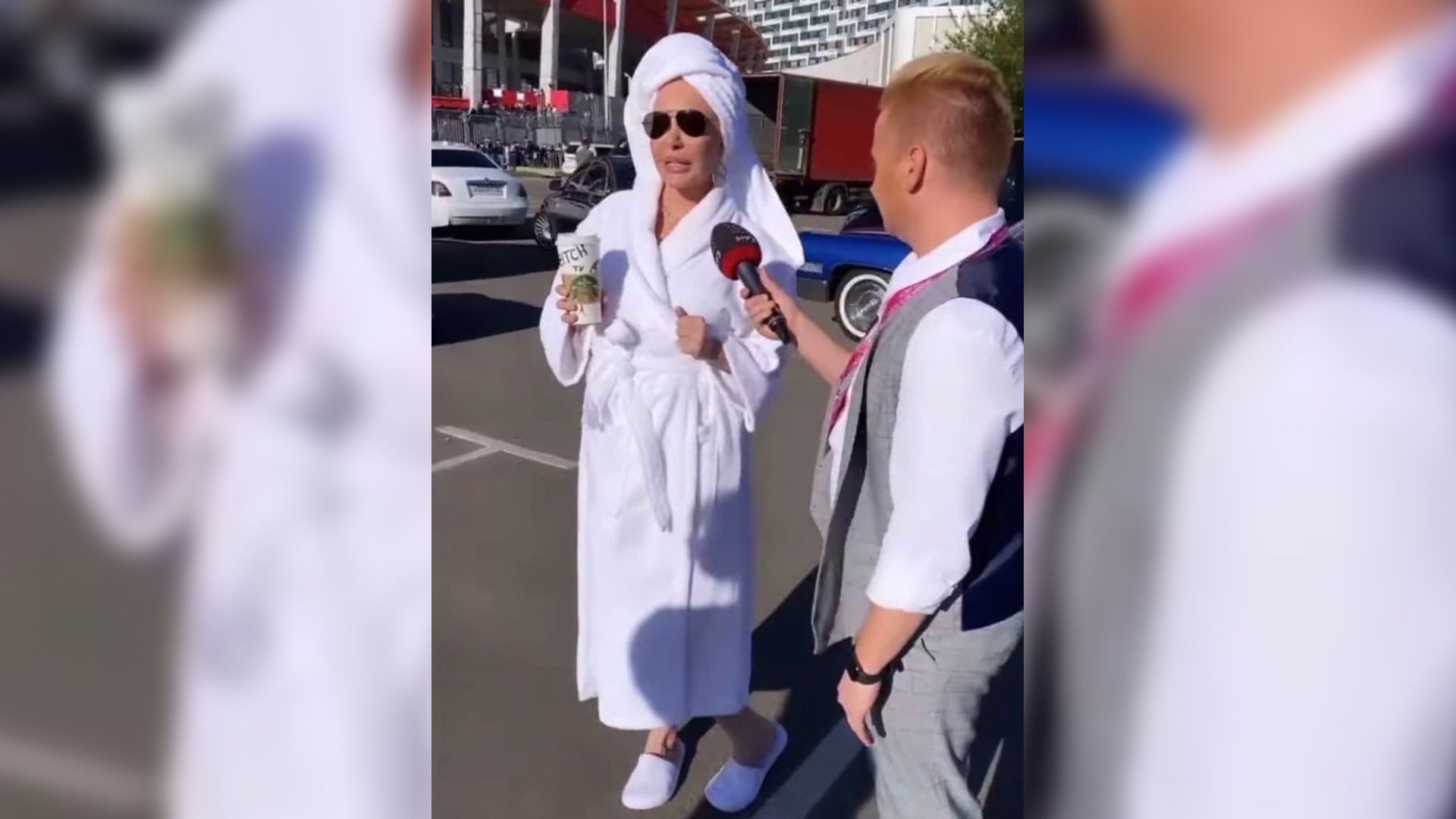 Мала Малиновская стоит на улице в белом халате и тапочках