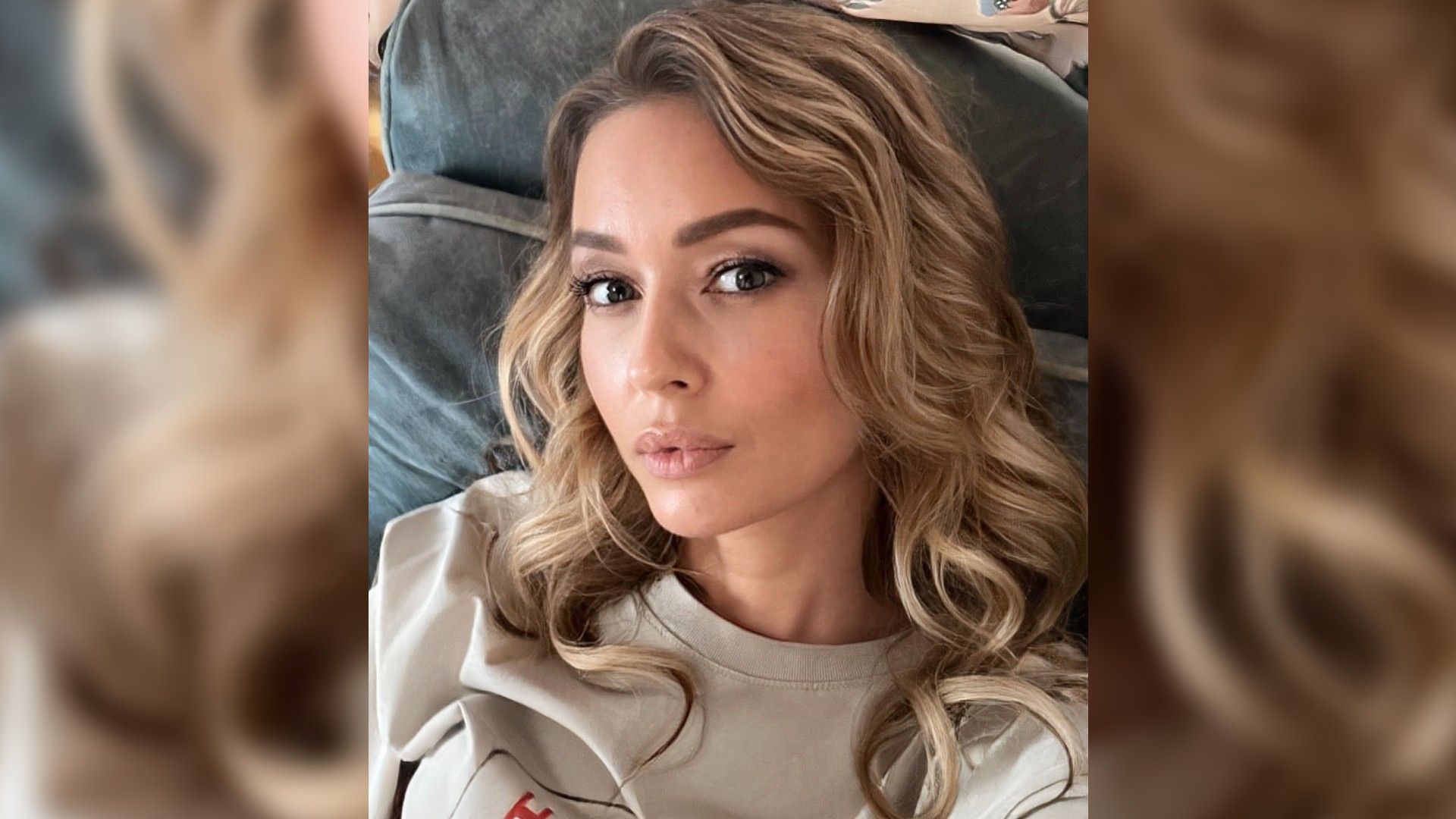 Евгения Лоза с причёской локонами делает селфи, лежа на кровати