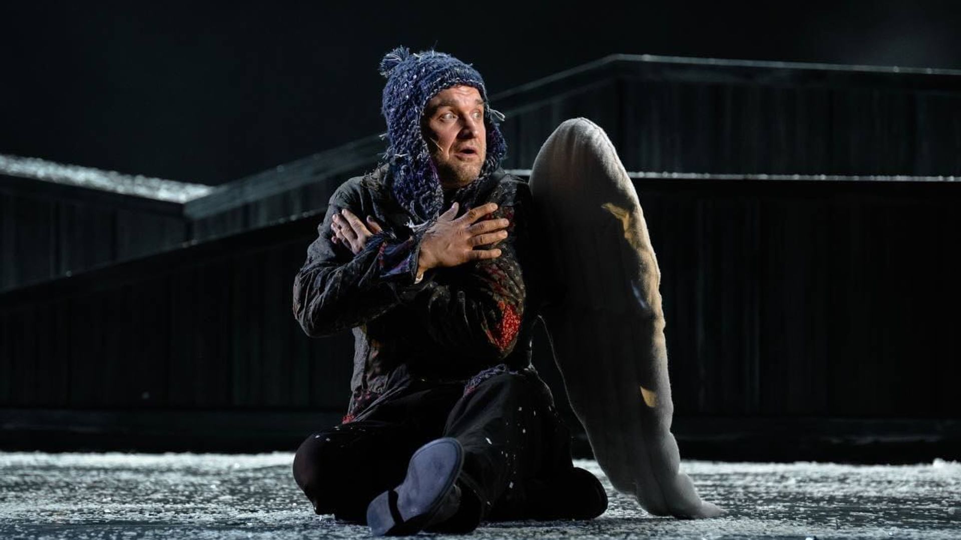 Иван Замотаев в шапке и с крыльями ангела сидит на сцене