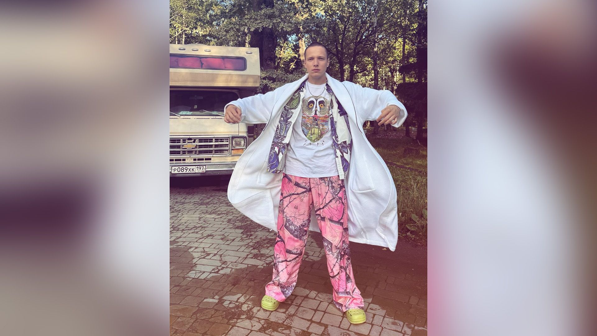 Сергей Городничий в широких розовых штанах и белом банном халате стоит рядом с автофургоном