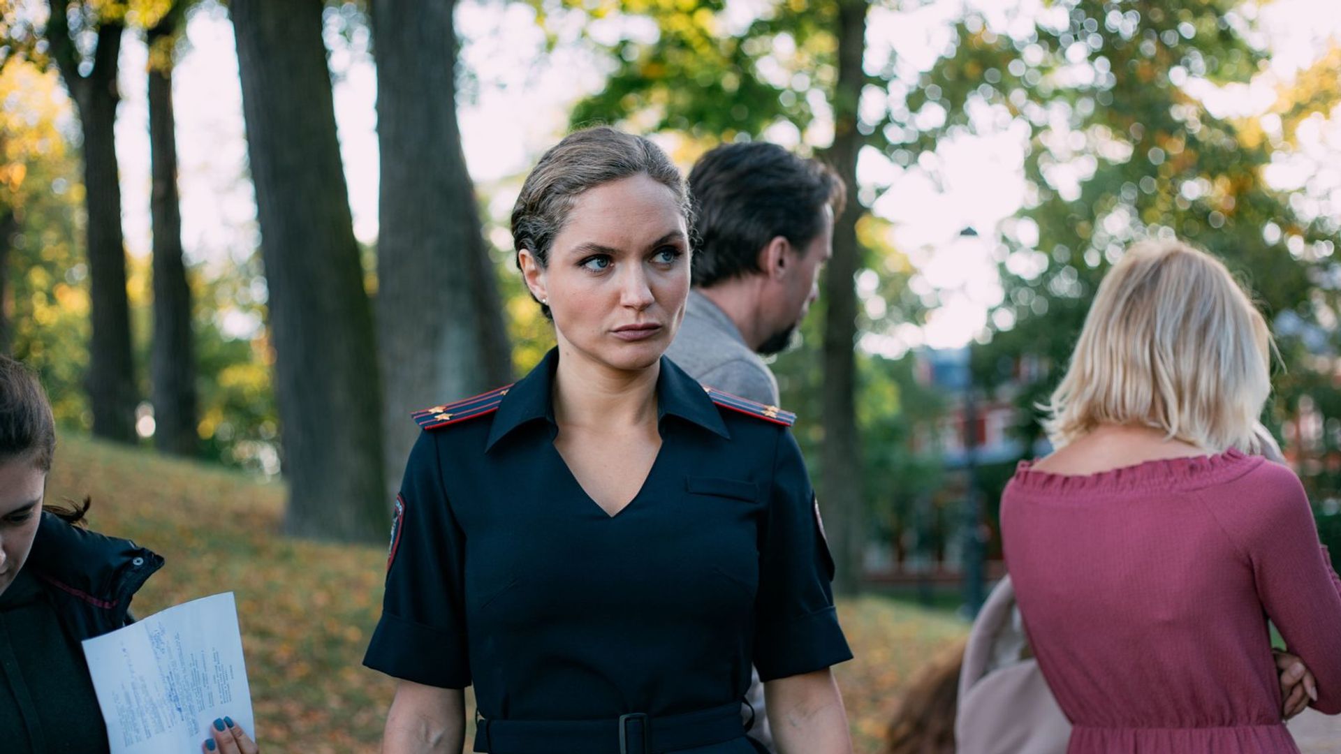 Евгения Шахнович в летней полицейской форме стоит на фоне природы, на заднем плане люди