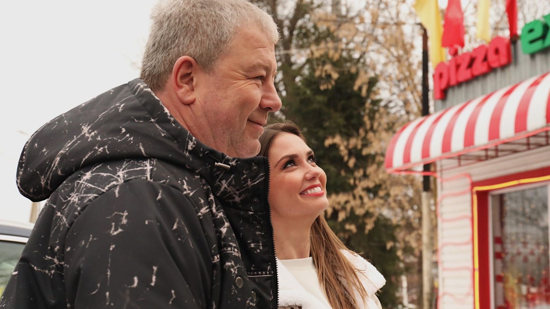 Александр Робак и Агата Муцениеце в зимней одежде обнимаются на улице