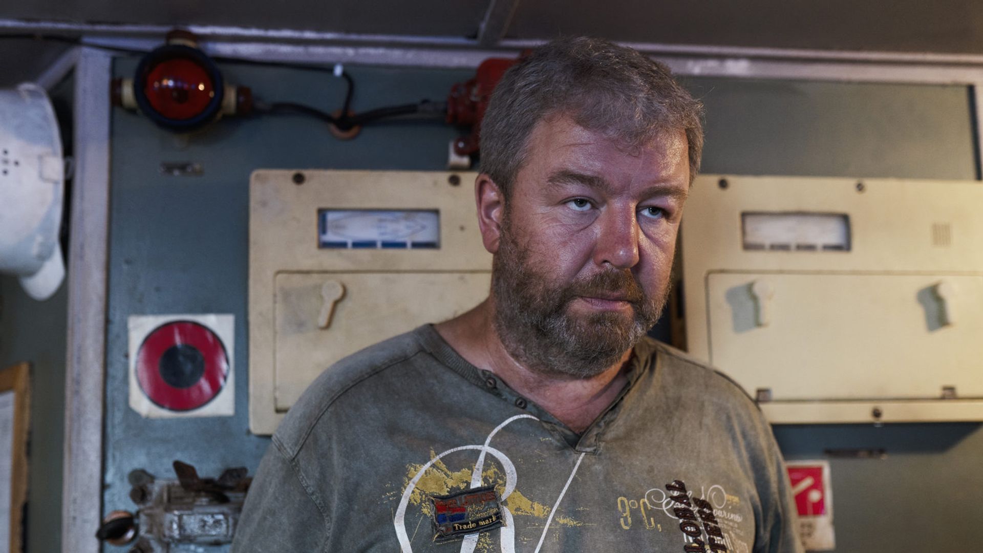 Александр Робак в потрёпанной серой футболке на фоне кабины корабля