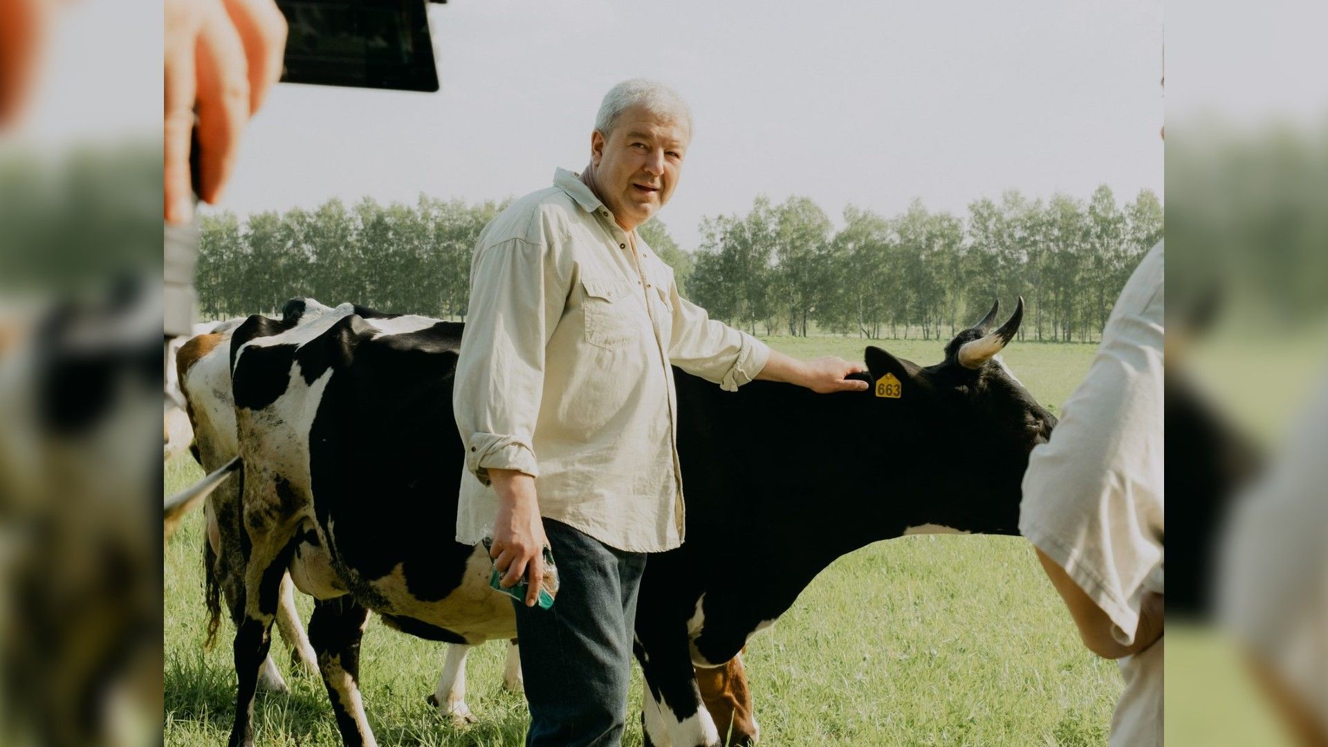 Александр Робак гладит корову на фоне природы