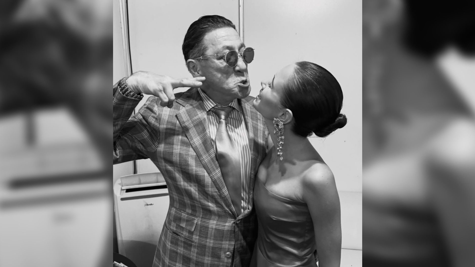 Григорий Лепс показывает руку Авроре Кибе, которая стоит спиной к камере, черно-белое фото