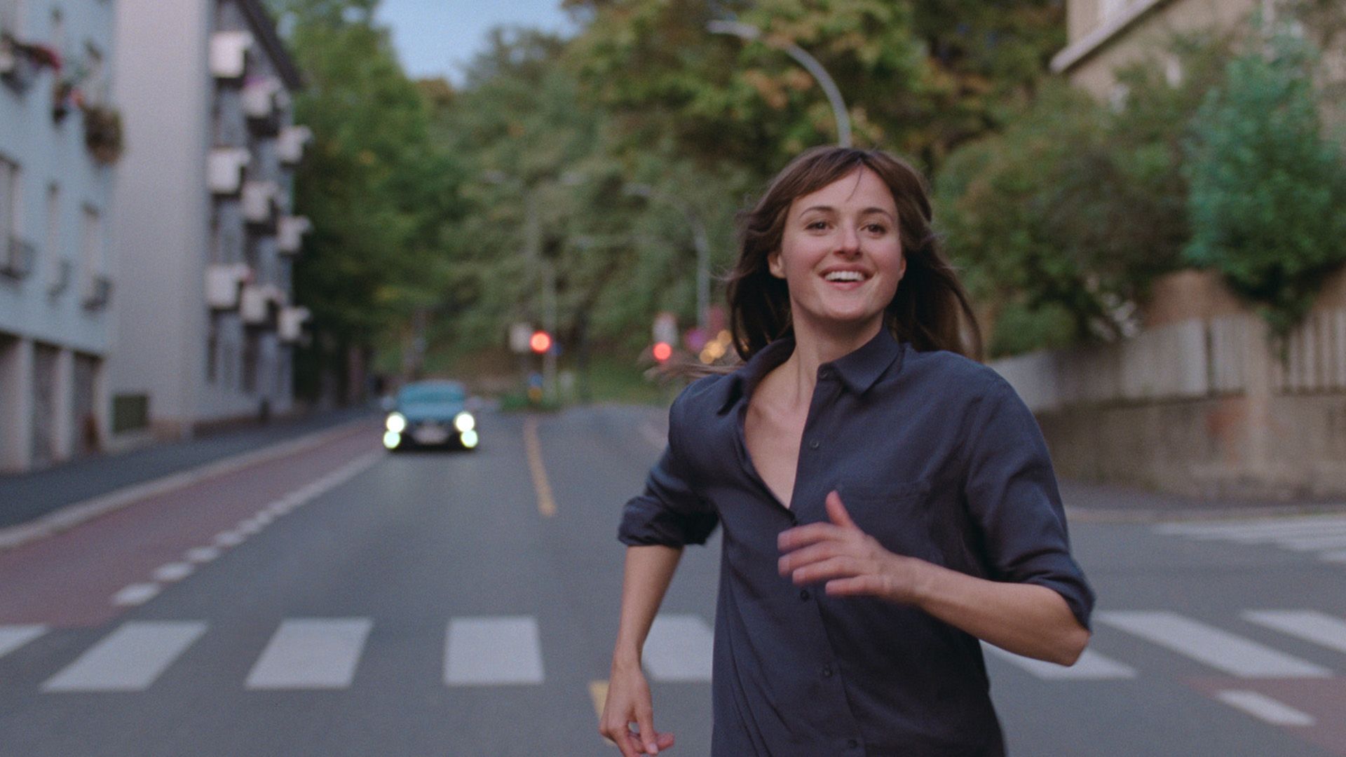 Ренате Реинсве в серой рубашке бежит по пустынной дороге, широко улыбаясь