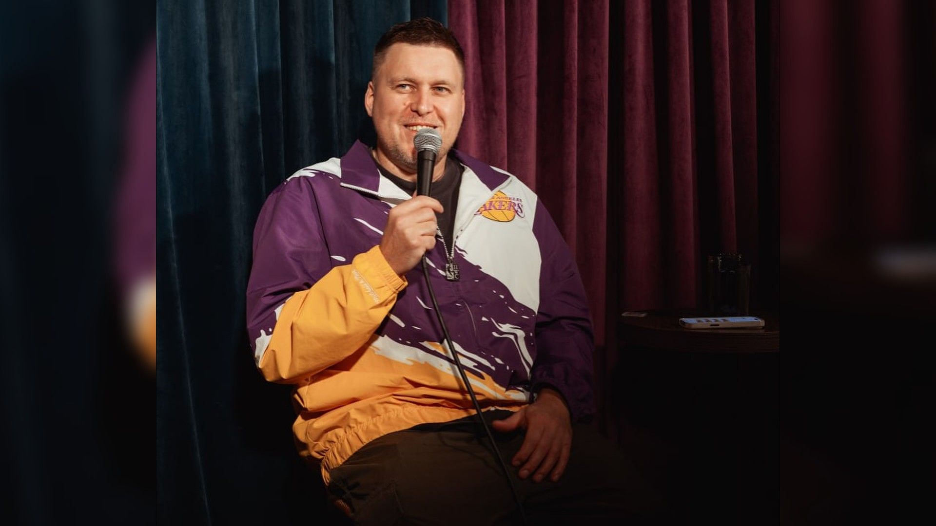 Александр Незлобин в спортивном костюме с микрофоном в руке