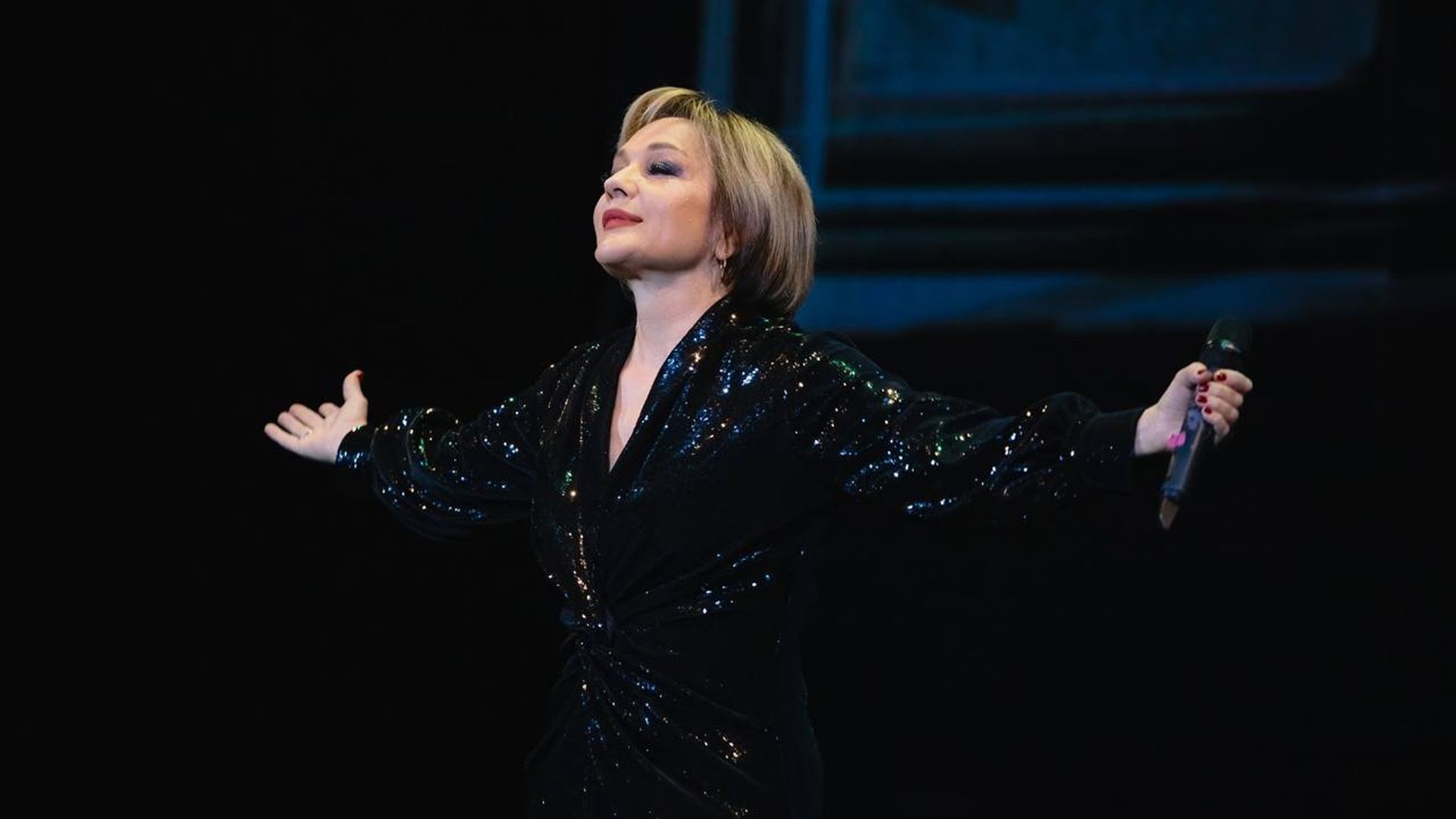 Татьяна Буланова стоит на сцене, разведя руки в стороны