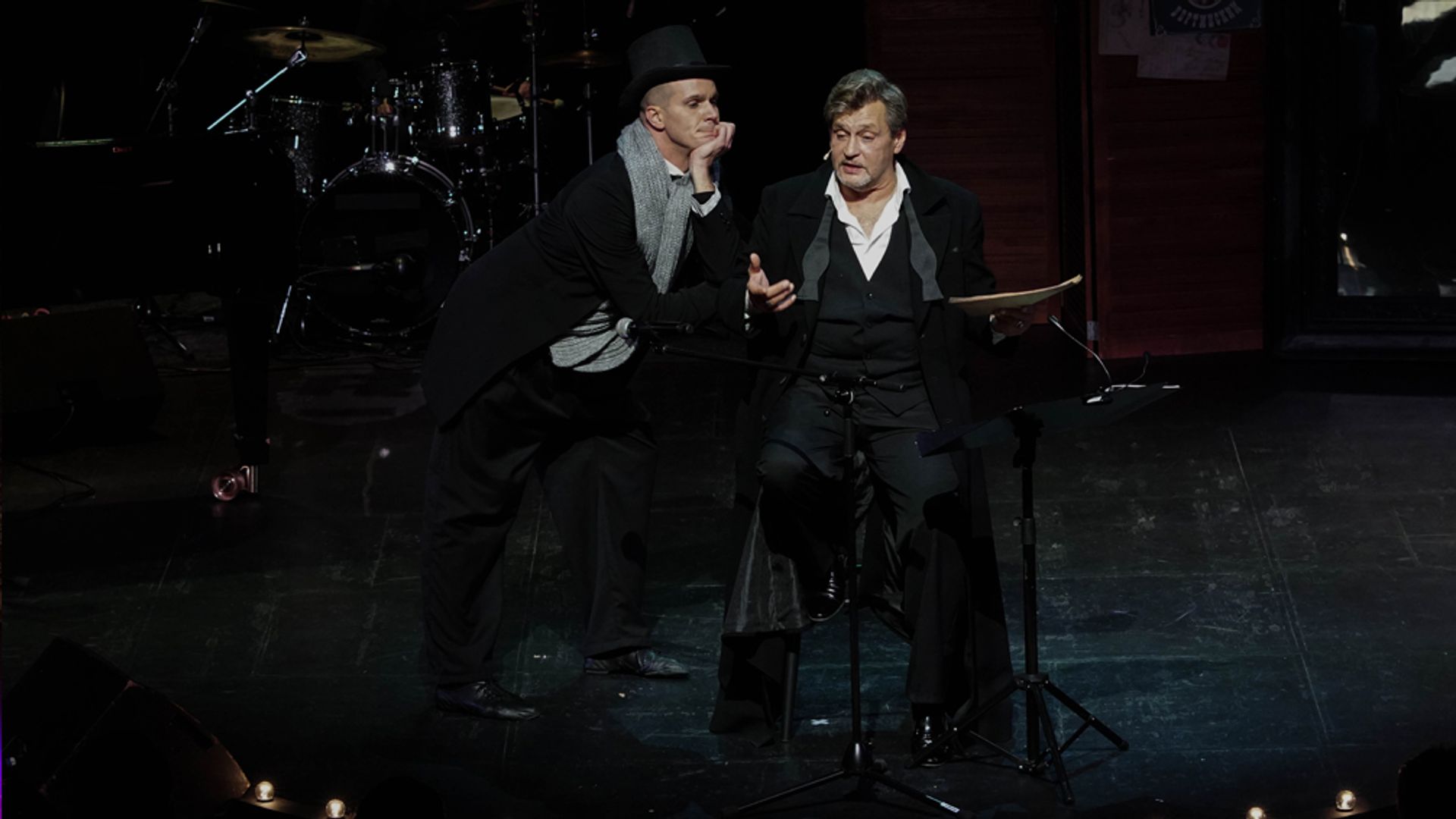 Два актёра сидят на сцене в полутьме