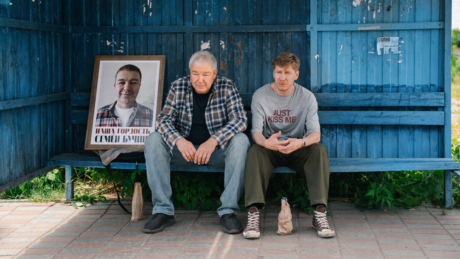Алексей Корсуков и Александр Робак сидят на синей автобусной остановке